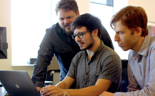Azavea R&D team members gathered around a laptop