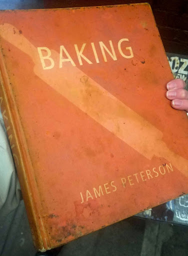An orange book with the title "Baking" by James Peterson